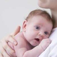Portrait of newborn baby held by his/her mother, studio shot